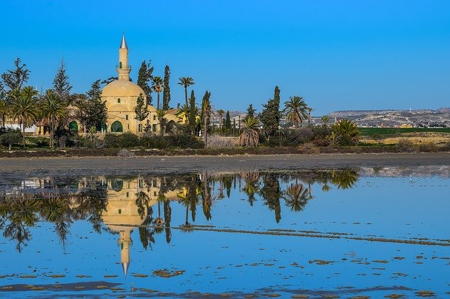 Larnaca Cyprus, stone building with minaret at water's edge with blue sky