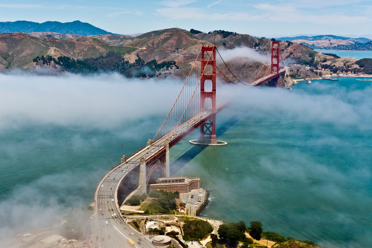 San Francisco's Golden Gate Bridge with green blue ocean and mist above the gate's famous copper towers